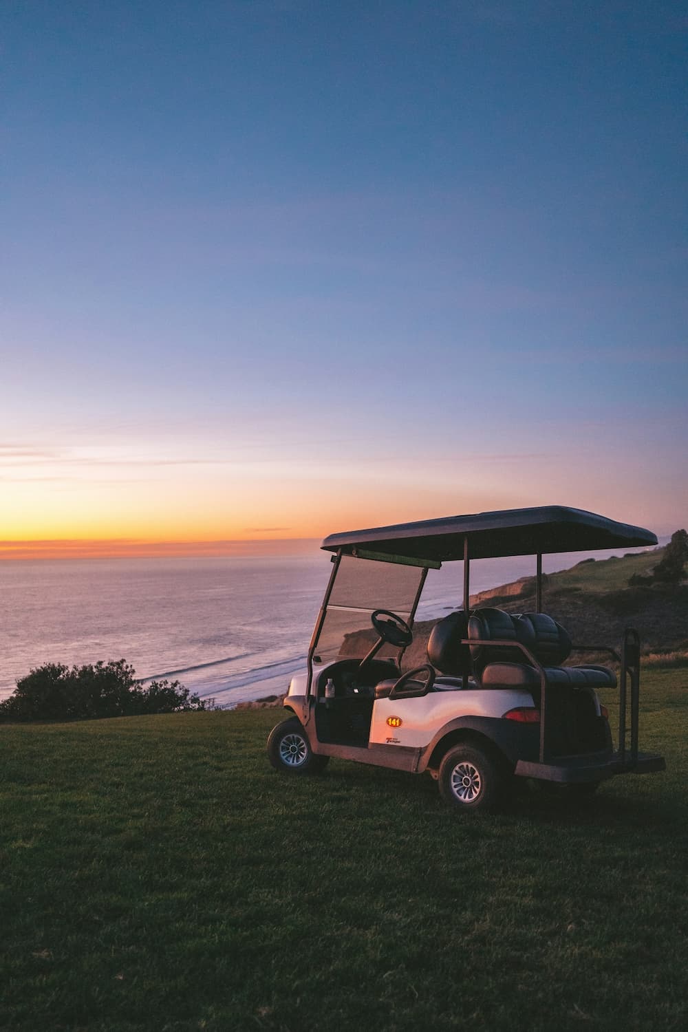 Golf cart parked on a beach with ocean waves in the background