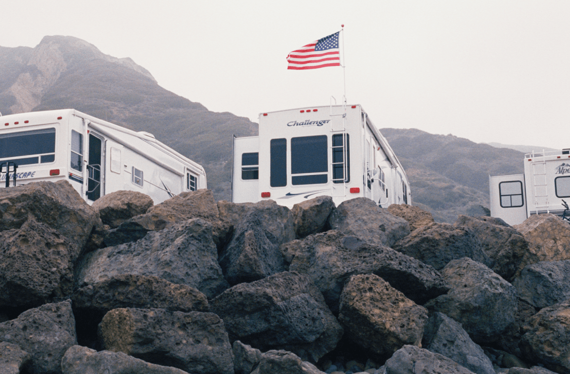 RVs parked near mountains with American flag