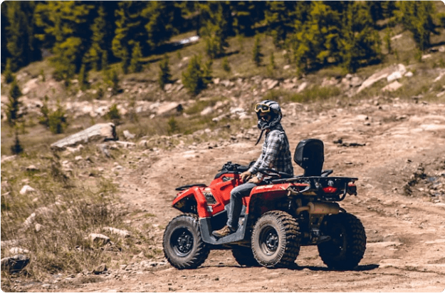 Person riding red ATV on mountain trail