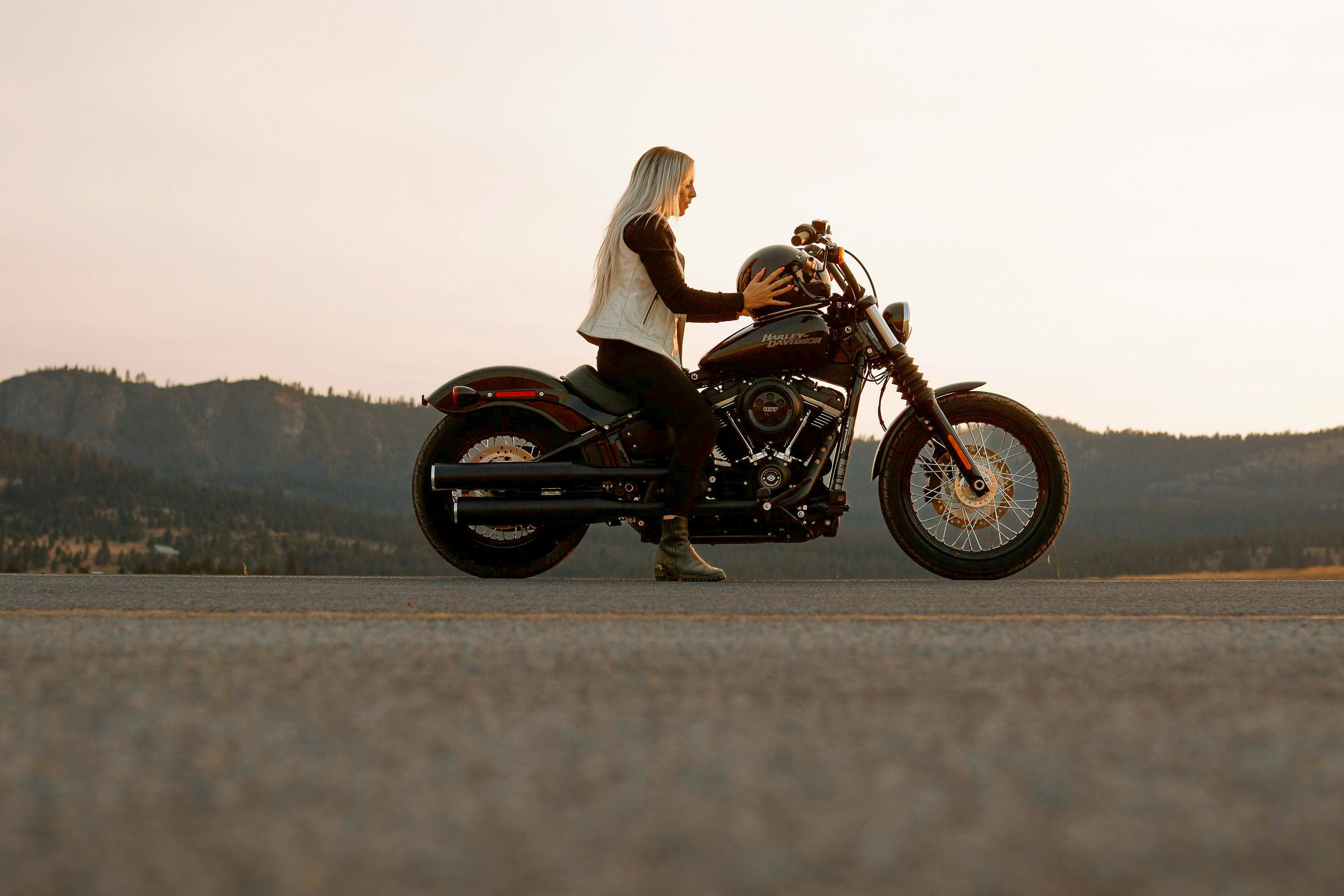 Woman on a motorcycle putting on a helmet, ready for an adventure