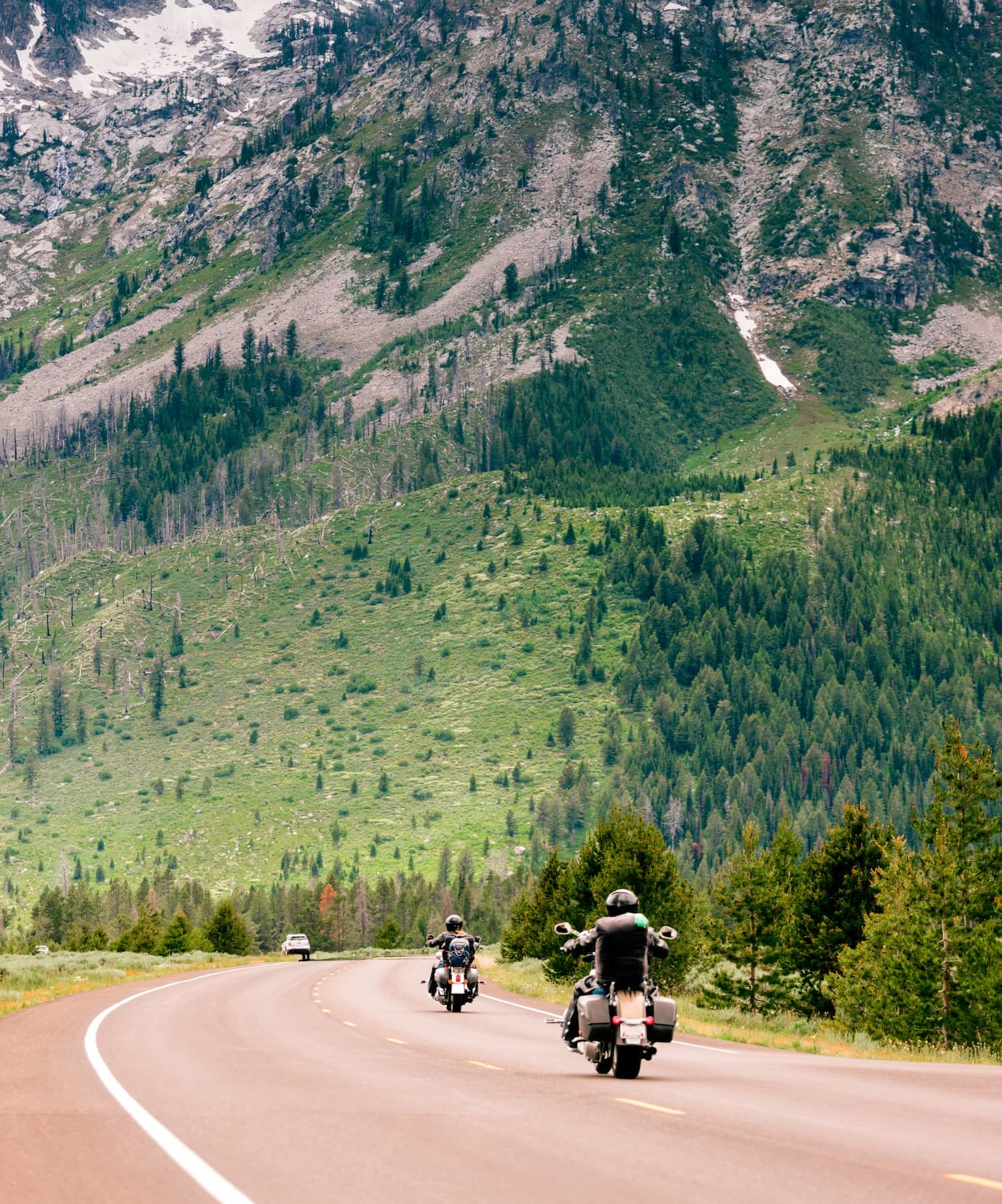Group of motorcyclists riding on a scenic road with mountains in the background