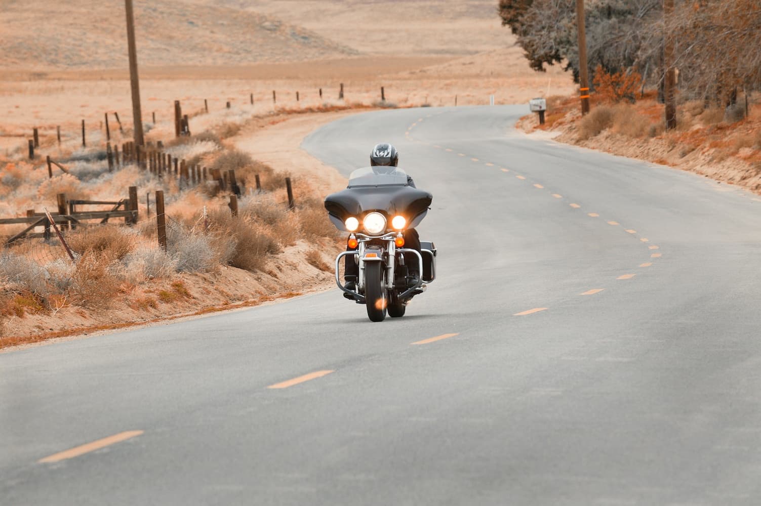 Motorcycle rider on winding desert highway through red rock landscape